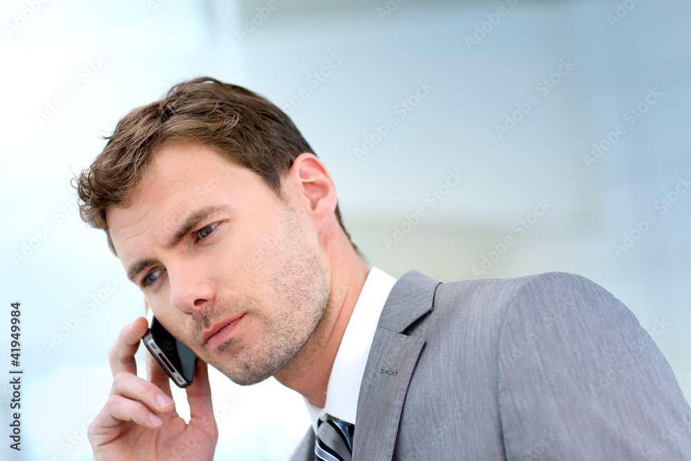 Businessman having a phonecall in building hallway Businessman having a phonecall in building hallway