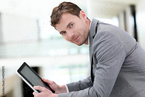 Portrait of businessman using electronic tablet in hall