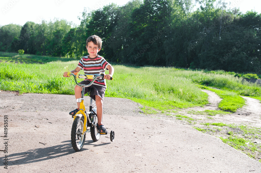 Obraz premium Little boy riding bike on country road outdoors