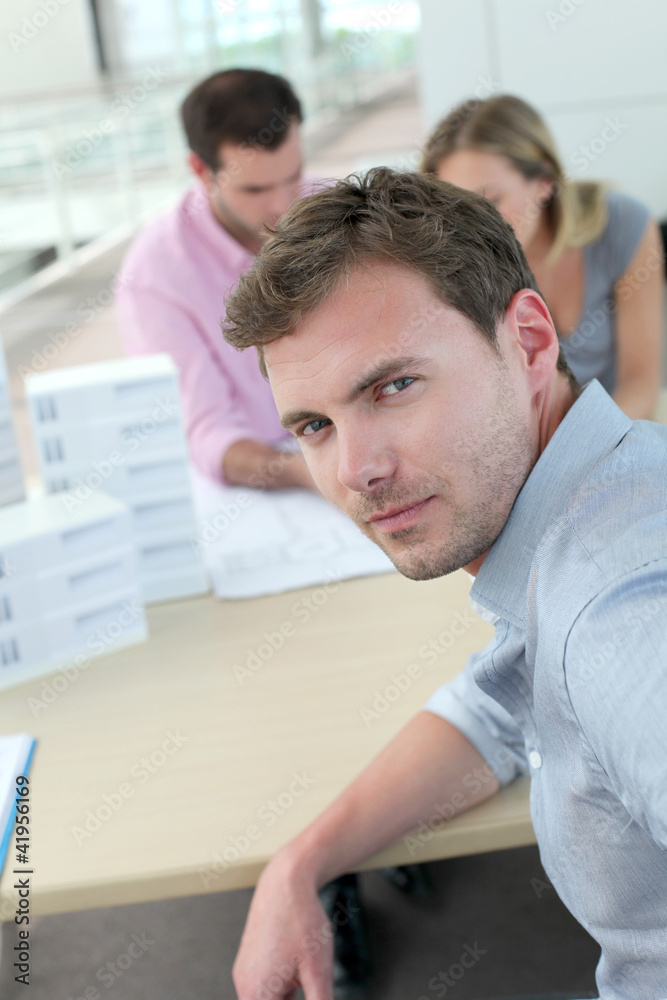 Portrait of man sitting in office with colleagues Portrait of man sitting in office with colleagues