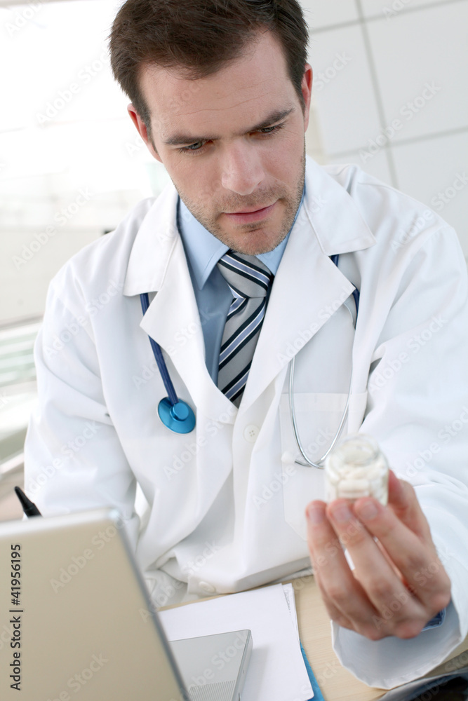 Doctor with laptop computer checking medicine composition