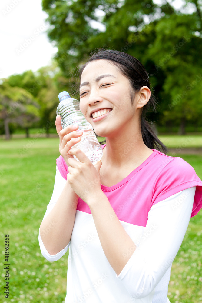 young asian woman drinking water in the park young asian woman drinking water in the park