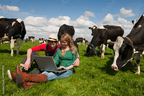 Young couple farmers in field with cows photo