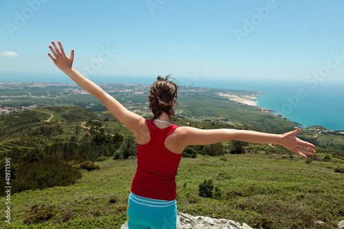 Fitness girl on top of rocks with arms wide open