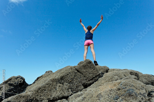 Fitness girl on top of rocks with arms wide open