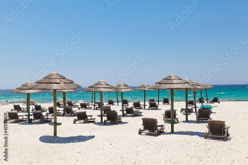 Deckchairs and parasols on sunny beach