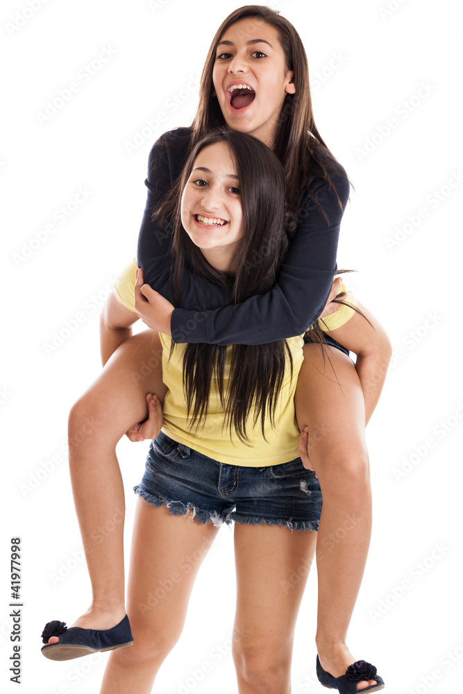 Preteen and teen sisters on piggyback isolated on white Stock Photo