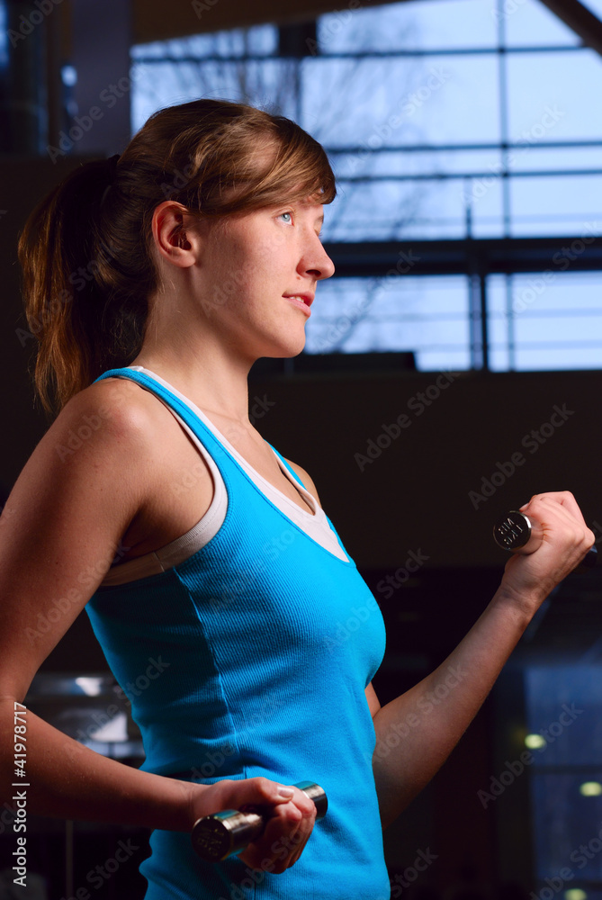 beautiful woman is exersising in gym at evening