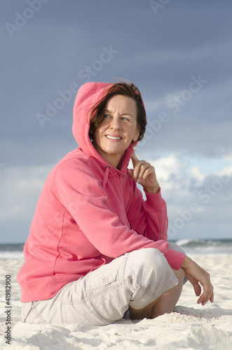 Happy relaxed mature woman sitting at ocean