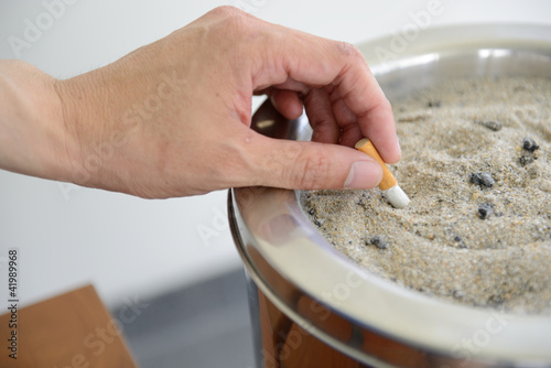 Fotografía Male hand Stubbing Out Cigarette in sand ashtray bin