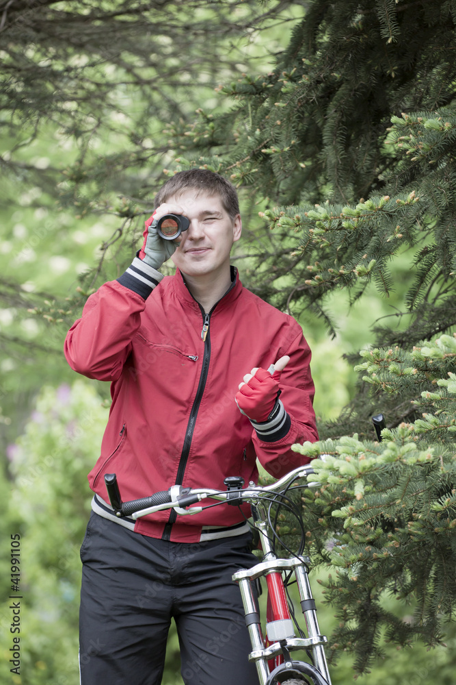 The man with a bicycle looks in monocular The man with a bicycle looks in monocular