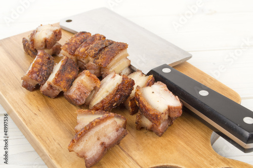 Siu Yuk - Chinese roast pork belly on a board with a cleaver photo