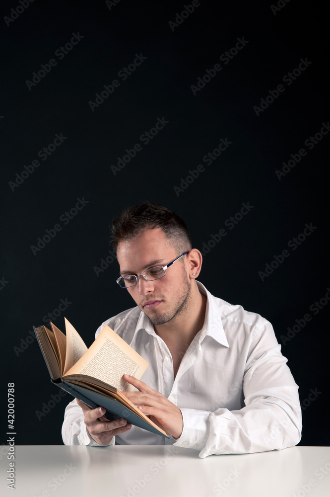 Young man reading a book against black background. Young man reading a book against black background.