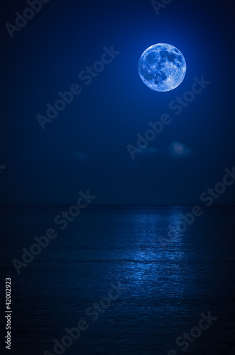 Bright full moon with reflections on the ocean © kmiragaya