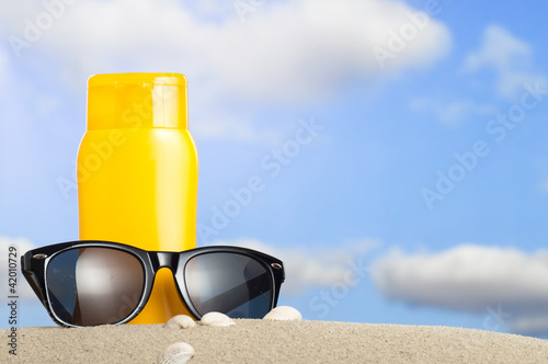 Tube with sun protection and sunglasses on beach