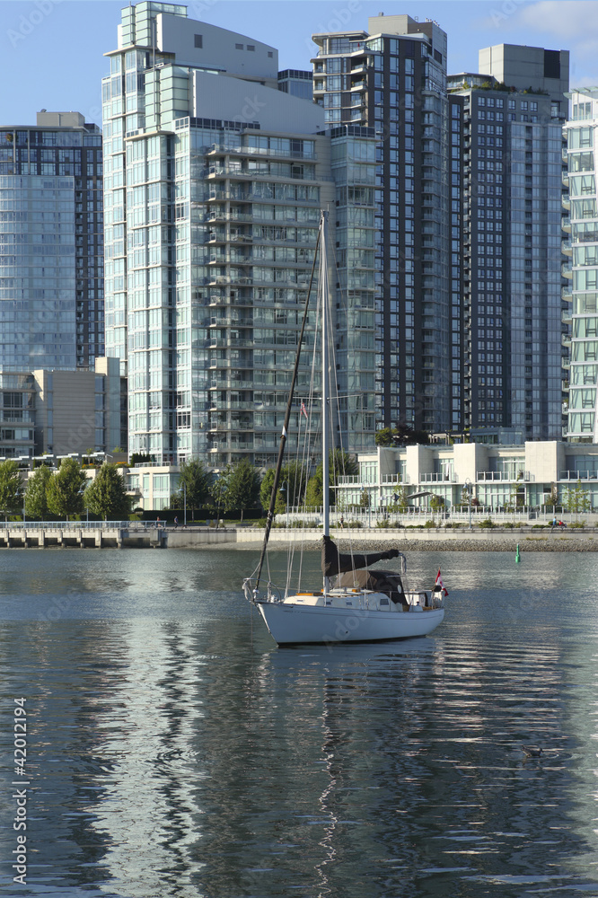 A sailboat and modern buildings in Vancouver BC canada.