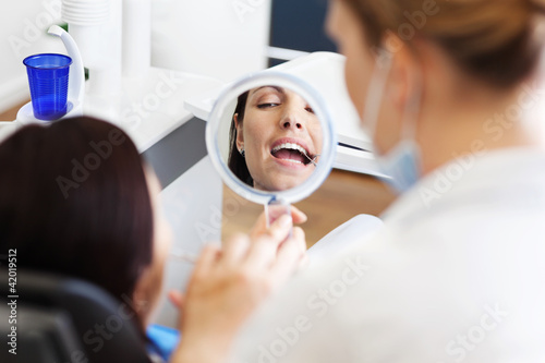 frau beim zahnarzt schaut in einen spiegel