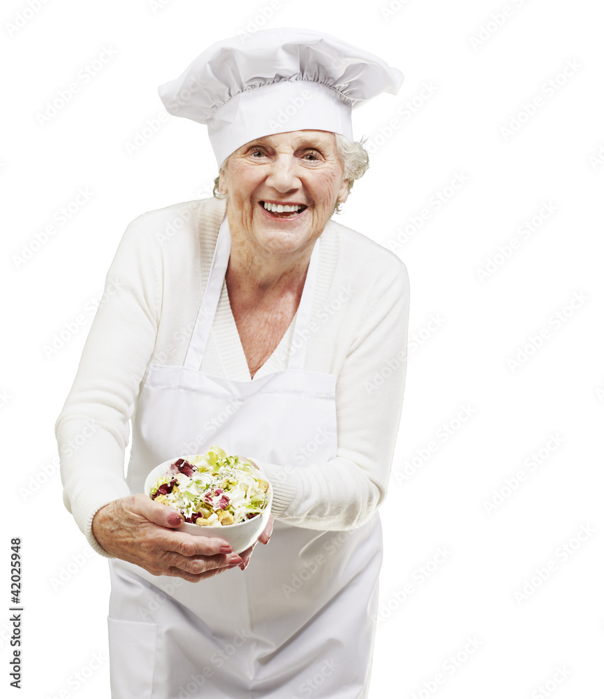 senior woman cook holding a bowl with salad against a white back senior woman cook holding a bowl with salad against a white back
