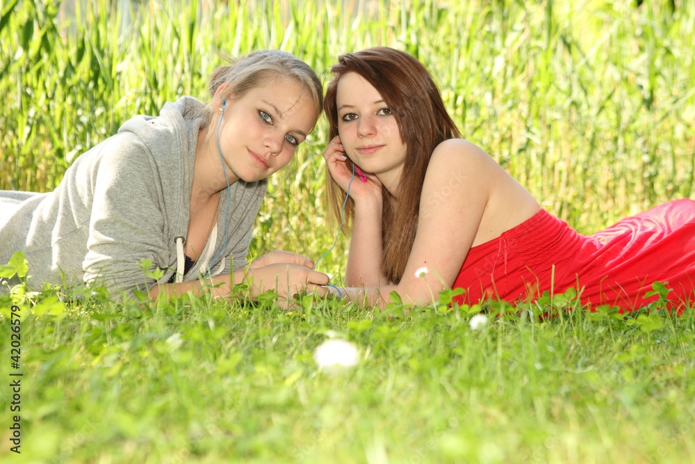 young teenager girls sharing music on a meadow young teenager girls sharing music on a meadow