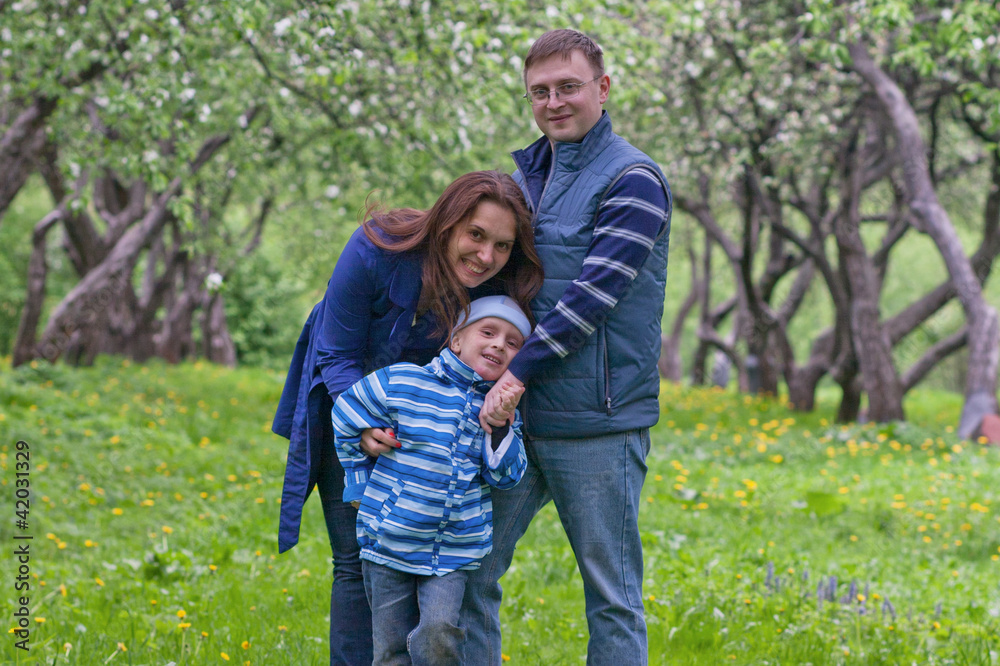 Fototapeta premium Happy young family of three have fun in apple garden