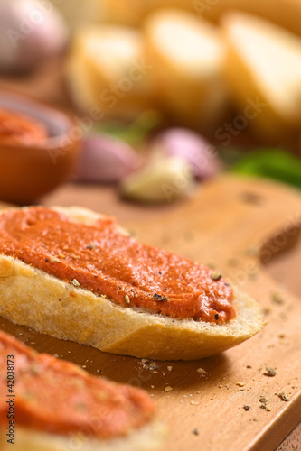 Tomato-butter spread on baguette slices with ground pepper