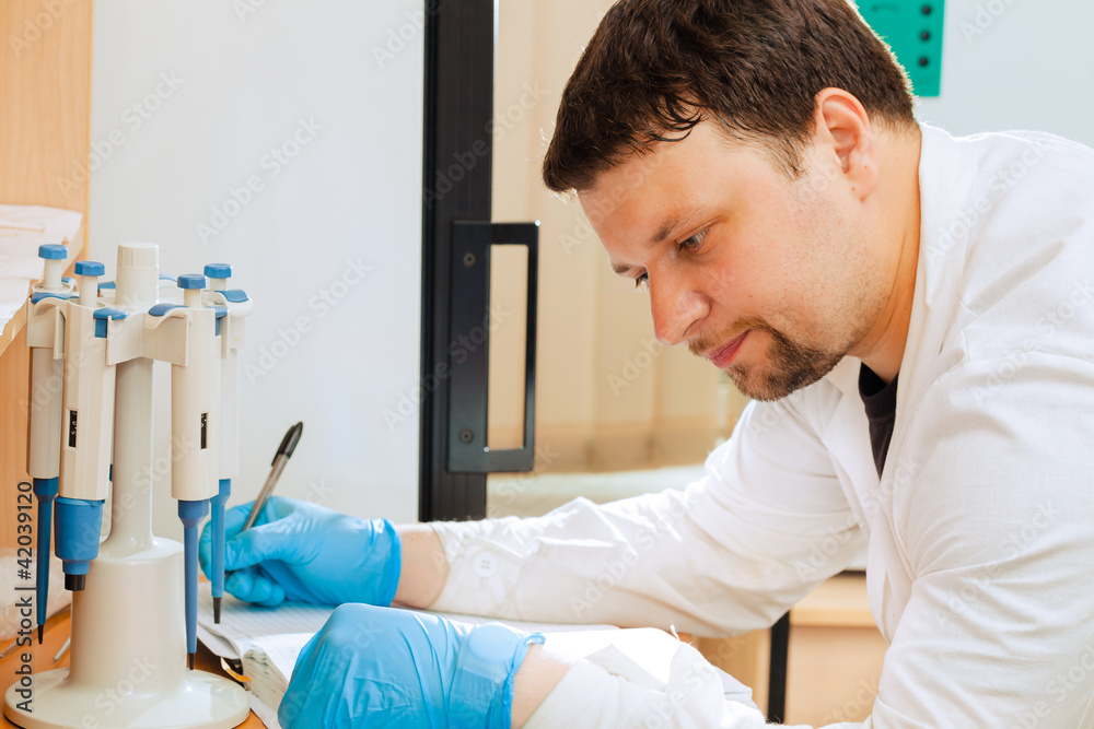 Researcher writing data into lab journal Researcher writing data into lab journal