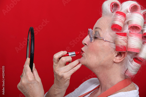 Woman with curlers putting on lipstick