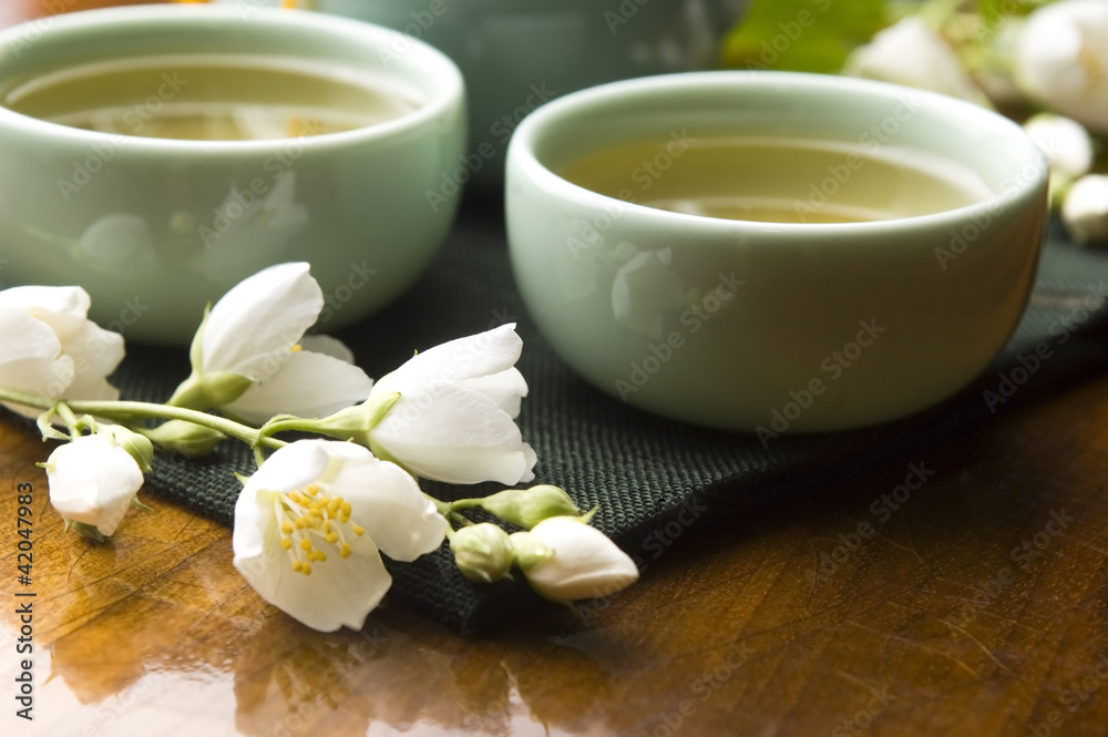 Green tea with jasmine in cup and teapot on wooden table