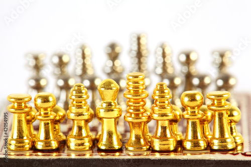 Gold and silver small chess stand on checkerboard; complete set