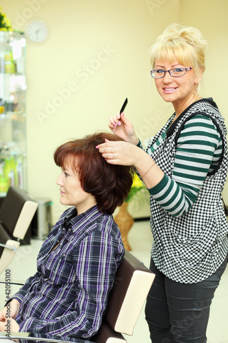 Hairdresser makes hair styling for woman by rake-comb photo