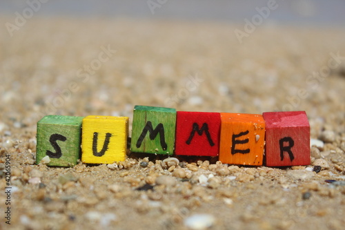 The word SUMMER written on wooden cubes, at the beach