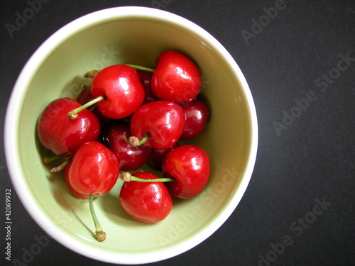 Red cherries a bowl on dark background, free space for text