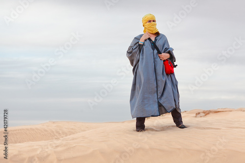 Valokuva Woman in bedouin clothes standing on dune in desert