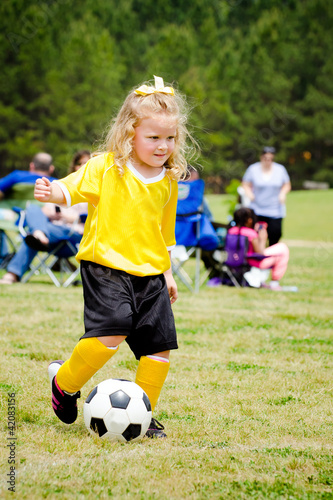 Girl in uniform playing in organized youth league soccer game