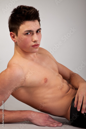 Healthy muscular young man on grey background