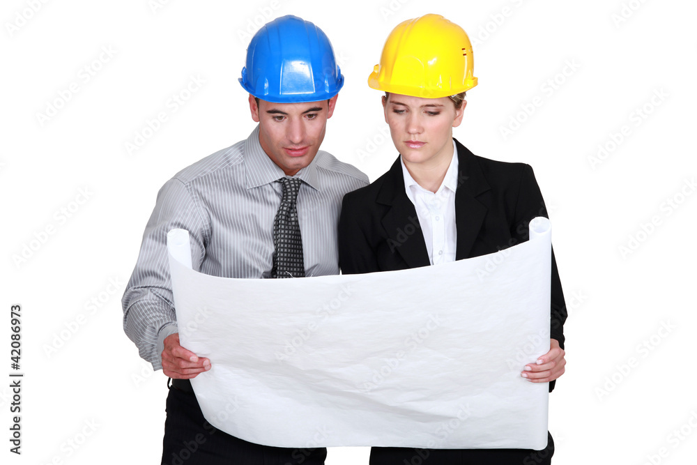 businesswoman and businessman looking at a blueprint businesswoman and businessman looking at a blueprint