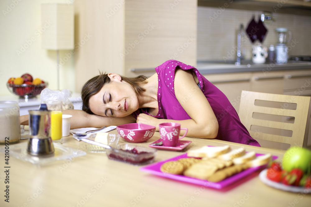 woman asleep on kitchen table during breakfast woman asleep on kitchen table during breakfast