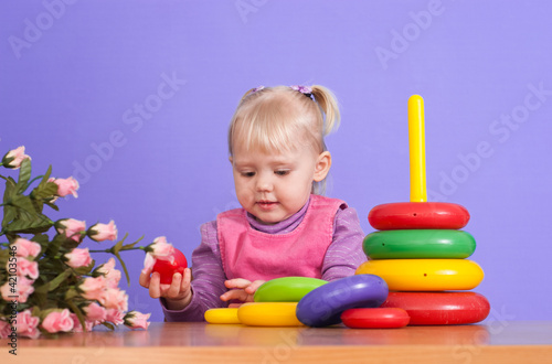A small charming Caucasian poppet plays with toy
