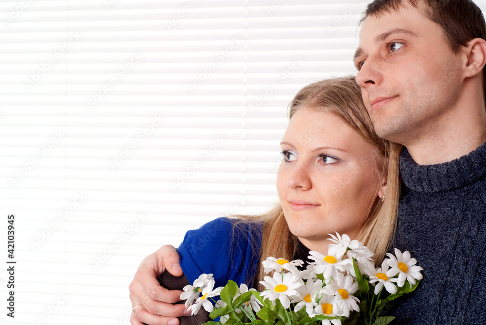 Happy good Caucasian couple with flowers stands