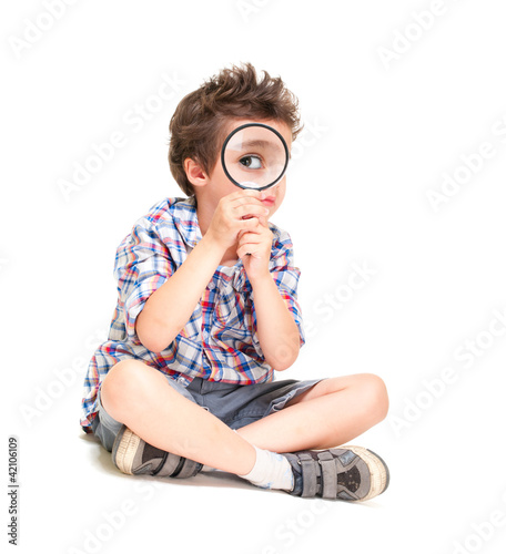 Attentive little boy with weird hair researching using magnifier