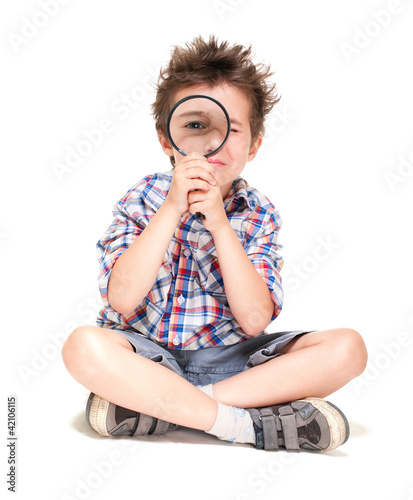 Attentive little boy with weird hair researching using magnifier