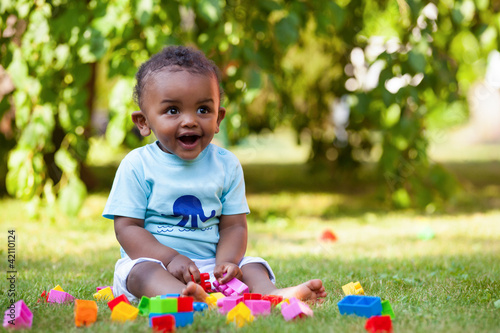 Little african american baby boy playing in the grass