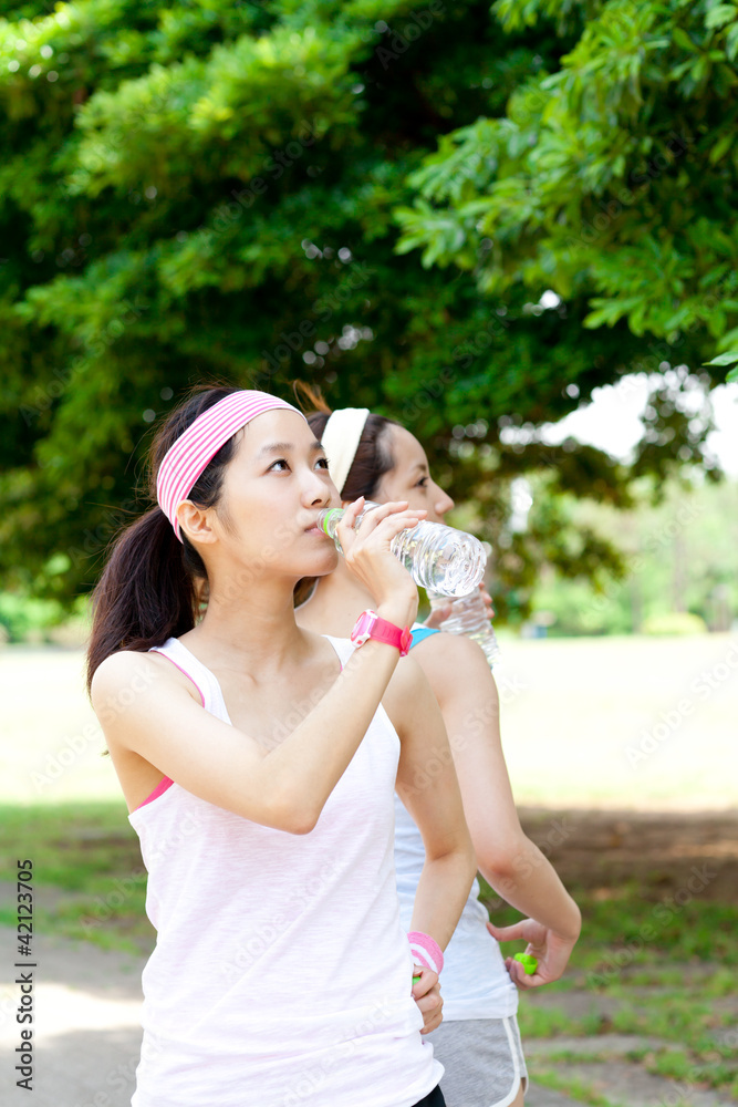 Obraz premium Beautiful young women drinking water at workout