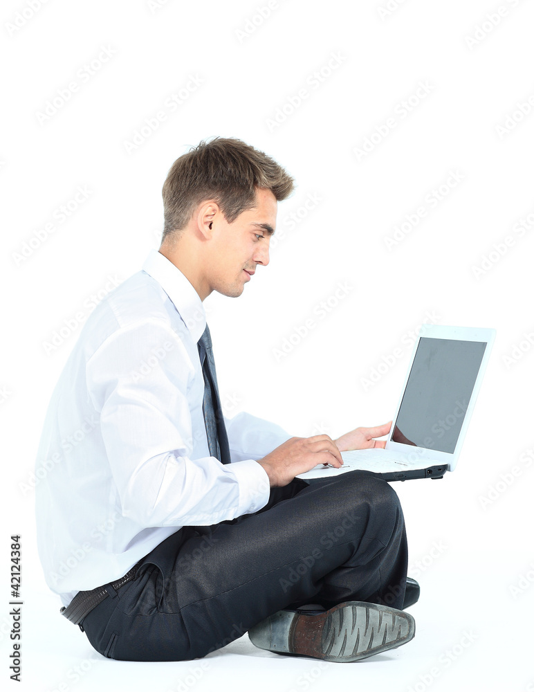 Isolated seated young businessman using a laptop