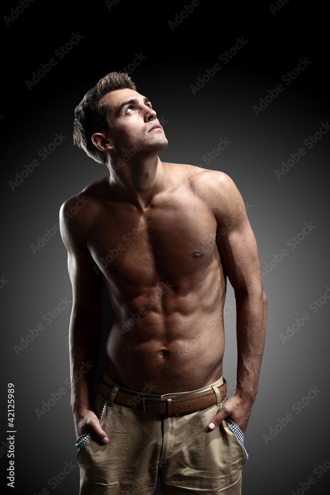 portrait of young strong man against black