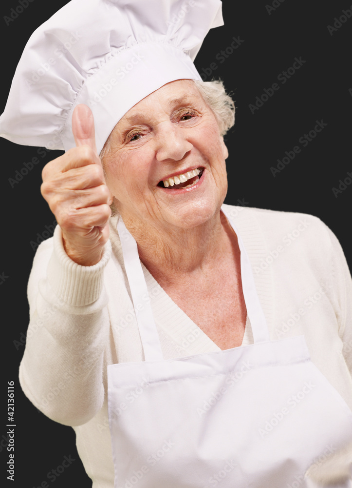 portrait of cook senior woman doing approval gesture over black portrait of cook senior woman doing approval gesture over black