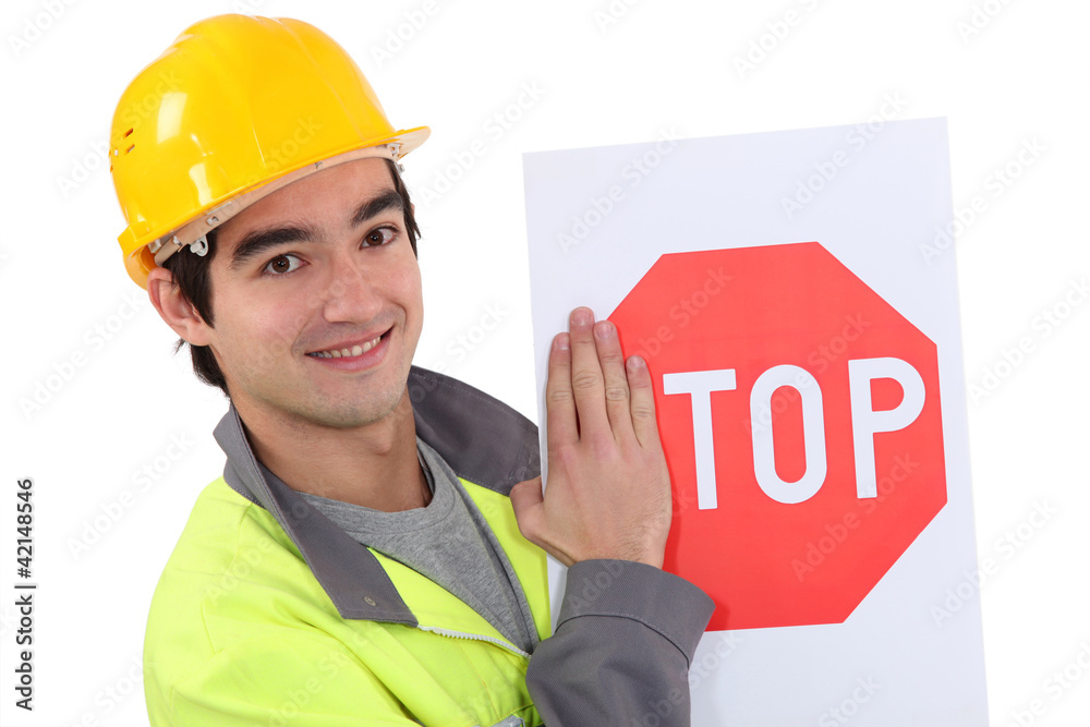 road worker hiding the letter s of a stop sign road worker hiding the letter s of a stop sign