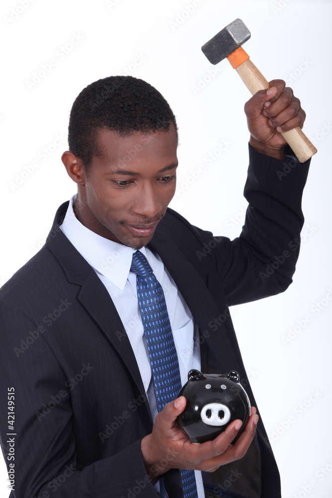 Naklejka premium Man breaking a piggy bank open with a hammer