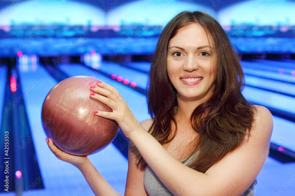 Happy young brunette woman holds ball and smiles in bowling club Happy young brunette woman holds ball and smiles in bowling club