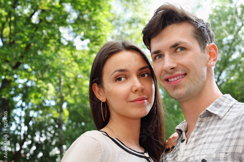 Beautiful smiling man and woman stand in park;
